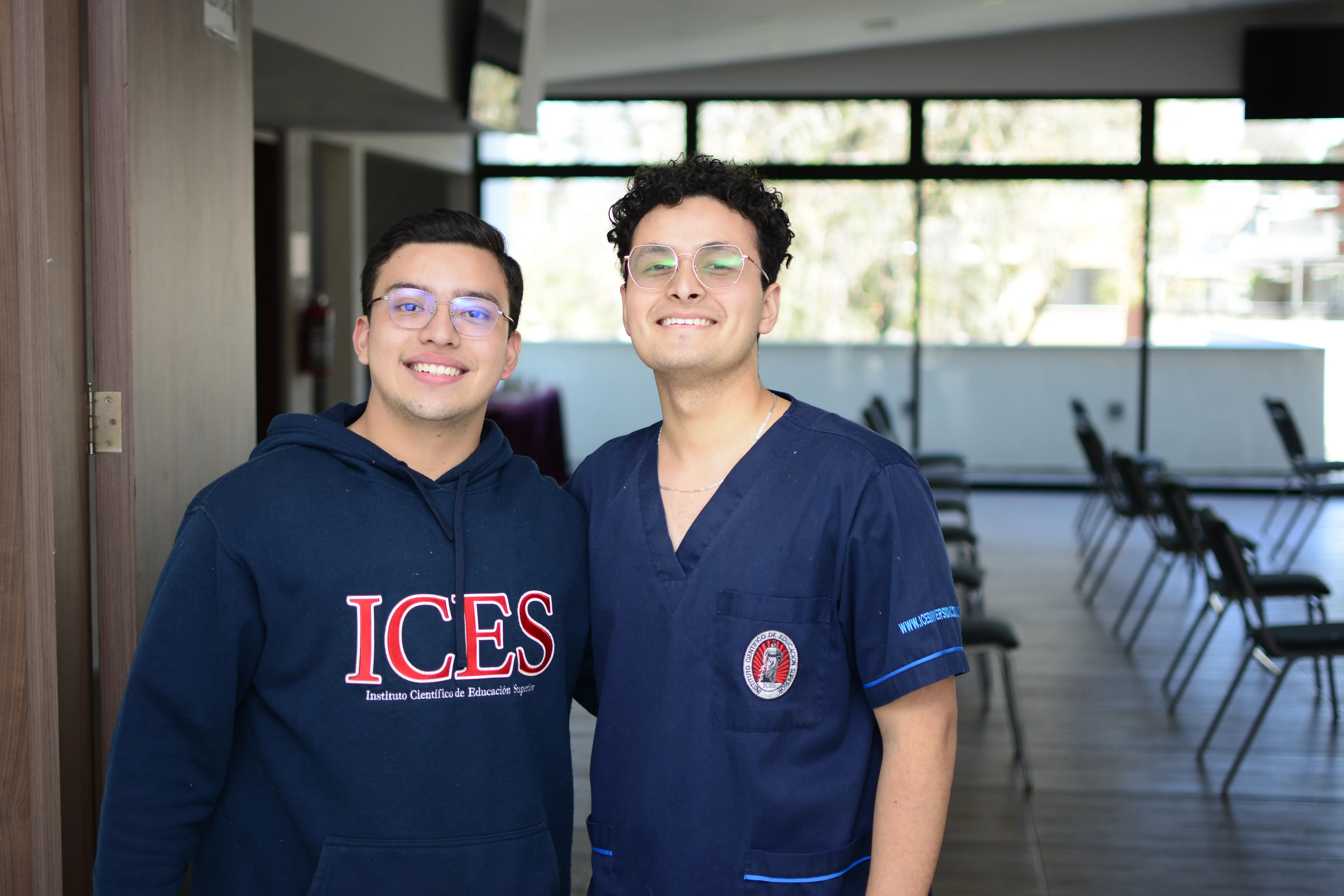 Dos estudiantes de ICES conversando en el pasillo del edificio principal